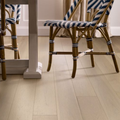 Dining area with light-colored hardwood flooring, navy and white striped bistro chairs, and a white dining table. The scene highlights the intricate chair patterns and warm, natural tones of the wood floor.